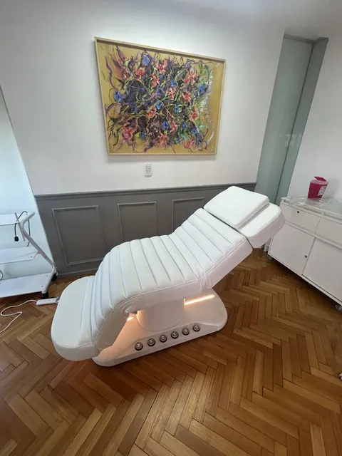 Camilla LUMA Premium blanca en un consultorio con piso de madera y un cuadro de flores.