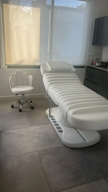 Camilla LUMA Premium blanca con una silla de respaldo curvo en un consultorio luminoso.