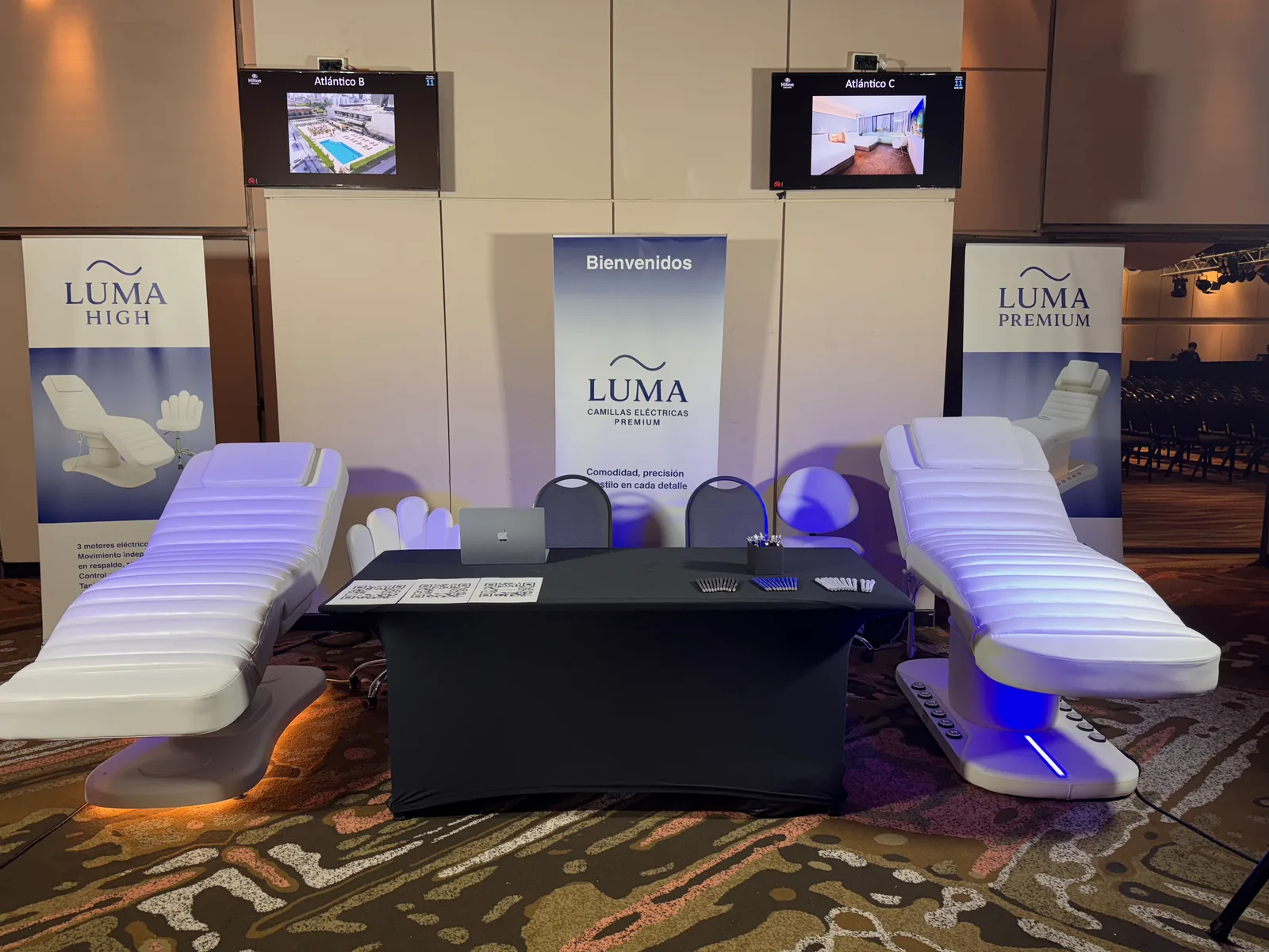 Espacio de LUMA en Masterhub con dos camillas eléctricas iluminadas y los banners de los modelos High y Premium.